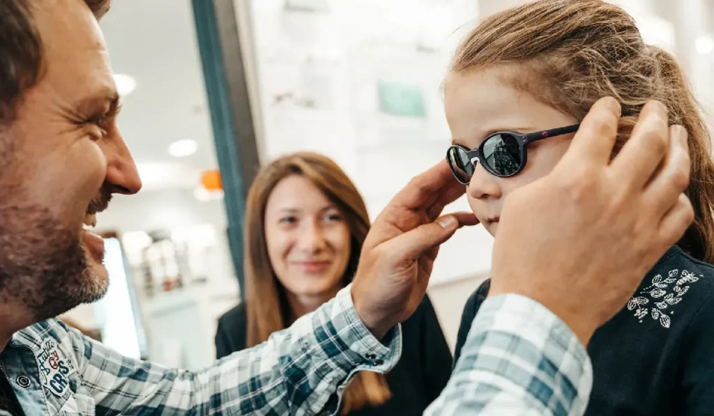 کودکی که چشم پزشک عینک آفتابی بر روی صورت او قرار داده